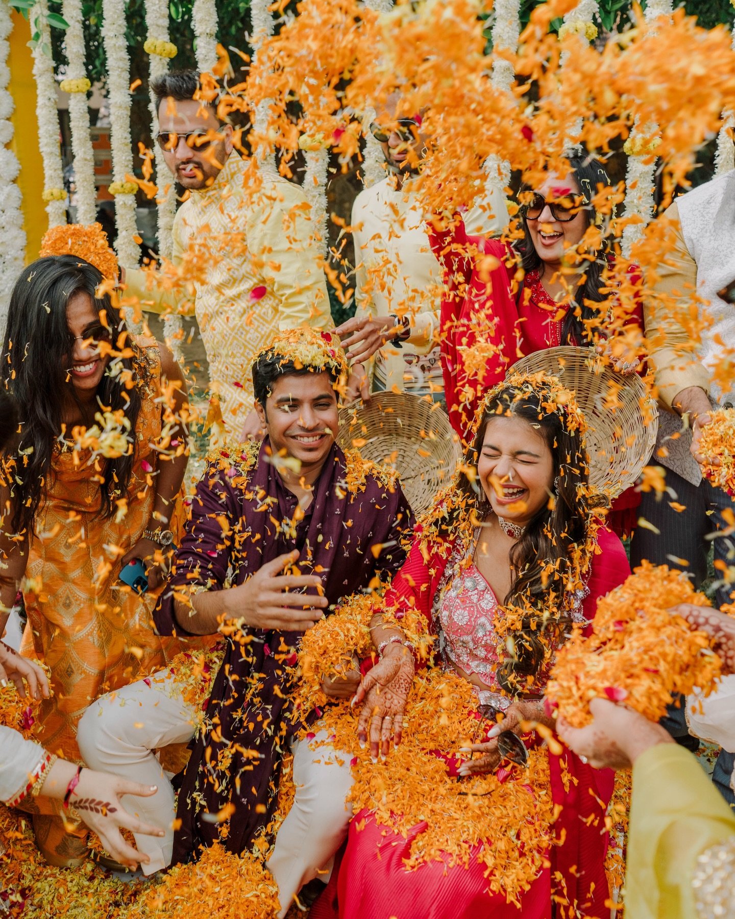 Friends showering a laughing couple with flower petals